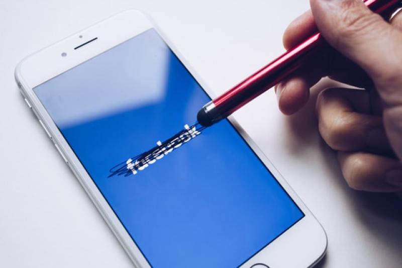 Person writing to erase Facebook's name on screen