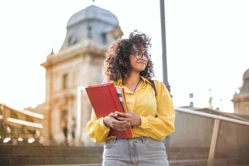 female student in yellow holding folders in school