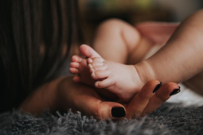 baby's feet held in hand by mom
