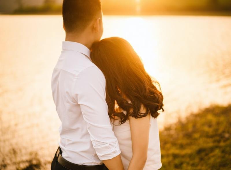 couple looking at reflection of sunset in body of water
